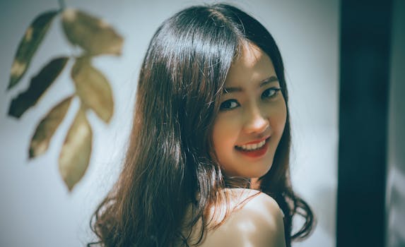 Portrait of a beautiful Asian woman with long hair smiling warmly, captured in an elegant studio setting.